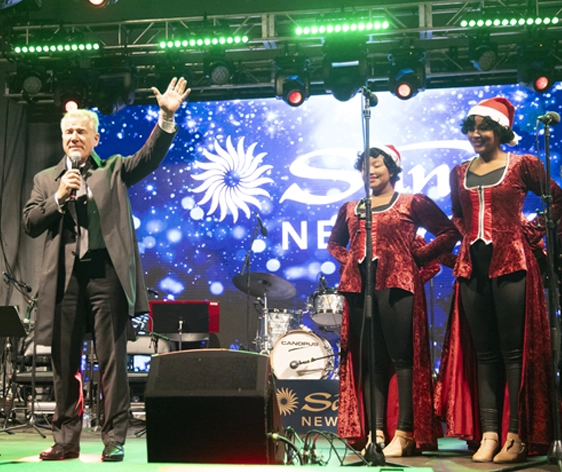 a man speaking at a Christmas benefit concert