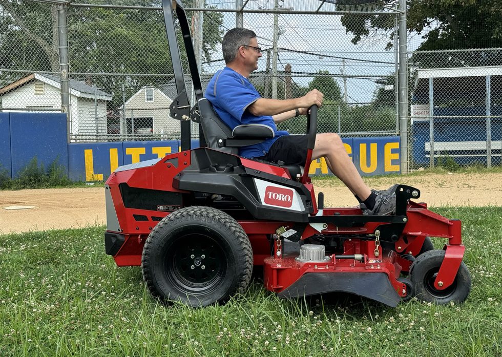 Man using ride-on mower at East Meadow Little League Inaugural Mow. 